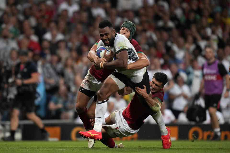 Fiji's Vilimoni Botitu, front, is tackled by Portugal's Nicolas Martins, left, and his teammate during the Rugby World Cup Pool C match between Fiji and Portugal, at the Stadium de Toulouse in Toulouse, France, Sunday, Oct. 8, 2023. (AP Photo/Pavel Golovkin)