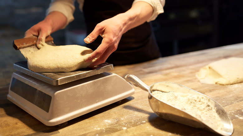 Person weighing dough on scale