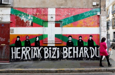 FILE PHOTO - A woman walks in front of a wall painted with a Basque flag on a house in the center of Bayonne, southwestern France, April 7, 2017. Words read: