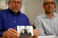Brothers Eli and Saul Lieberman show a photograph of their late father Joseph, a survivor of the Nazi death camp Auschwitz, taken several years after the Holocaust, during an interview with Reuters in Jerusalem