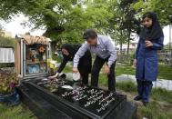 In this pictures taken on Monday, April 28, 2014, Iranian woman Samereh Alinejad, left, and her husband Abdolghani Hosseinzadeh wash the grave stone of their sons Amir Hossein and Abdollah while their daughter Fatemeh looks on in a cemetery in the city of Royan about 146 miles (235 kilometers) north of the capital Tehran, Iran. Amir Hossein was killed in a motorcycle crash and Abdollah was killed in a street brawl. Alinejad tells The Associated Press that she had felt she could never live with herself if the man who killed her son Abdollah were spared from execution. But in the last moment, she pardoned him in an act that has made her a hero in her hometown, where banners in the streets praise her family’s mercy. (AP Photo/Vahid Salemi)