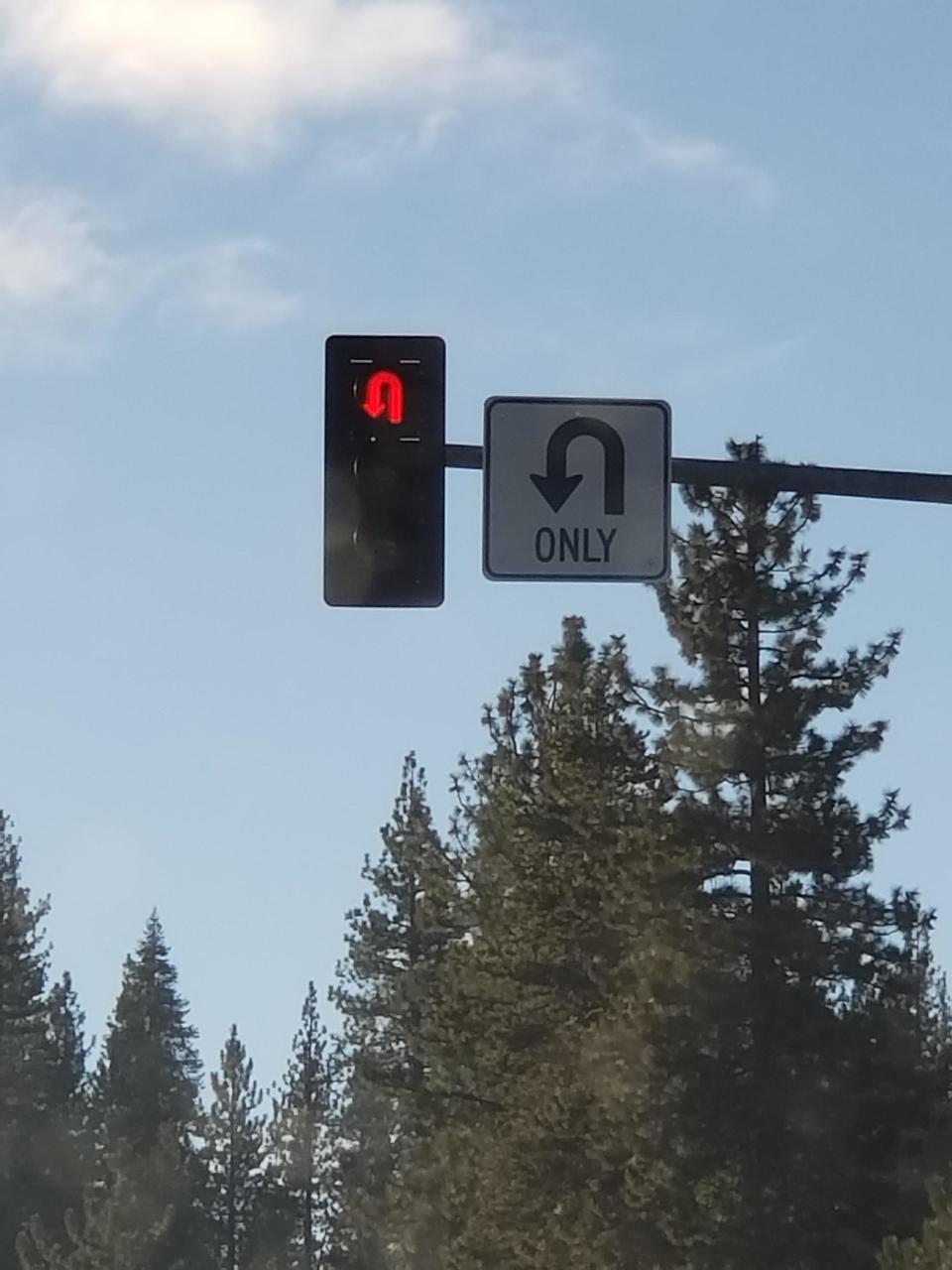 A red U-turn stoplight next to a "U-turn only" sign