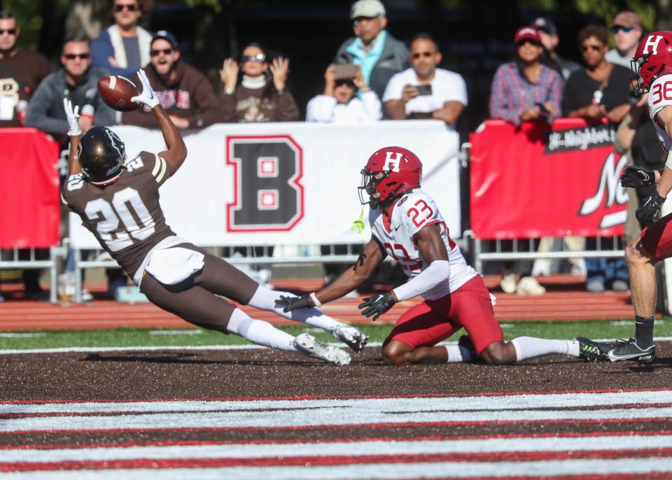 Brown's Allan Houston III lunges to make a catch as Harvard's Isaac Rollins (26) can only watch during Saturday's Ivy League opener for both teams in Providence. The Crimson won, 35-28.