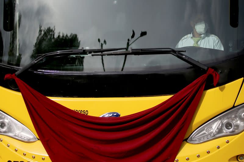 Un conductor de transporte intermunicipal usando una mascarilla es visto dentro de un autobús que tiene un trapo rojo colgando, durante una protesta para pedirle al gobierno reactivar sus trabajos, en medio del brote de COVID-19, en Bogotá, Colombia