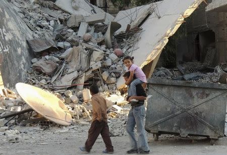 Children walk along a damaged street filled with debris in the Damascus suburb of Zamalka October 3, 2013. REUTERS/Bassam Al Arbeeni