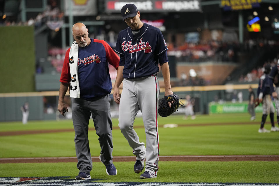 ADDS THE NAME OF THE TRAINER AT LEFT - Atlanta Braves starting pitcher Charlie Morton, right, is helped off the field by Braves head athletic trainer George Poulis, during the third inning of Game 1 in baseball's World Series between the Houston Astros and the Atlanta Braves Tuesday, Oct. 26, 2021, in Houston. (AP Photo/Ashley Landis)