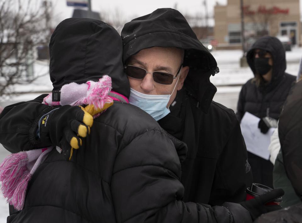 Steve Lydick, Scott Federer’s husband, hugs a friend at a vigil Sunday held at the bus stop where Federer was last seen Jan. 12.