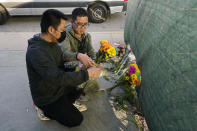 Two men place flowers near Star Dance Studio to honor victims killed in a shooting in Monterey Park, Calif., Sunday, Jan. 22, 2023. A gunman killed multiple people at a ballroom dance studio late Saturday amid Lunar New Years celebrations in the predominantly Asian American community of Monterey Park. (AP Photo/Jae C. Hong)