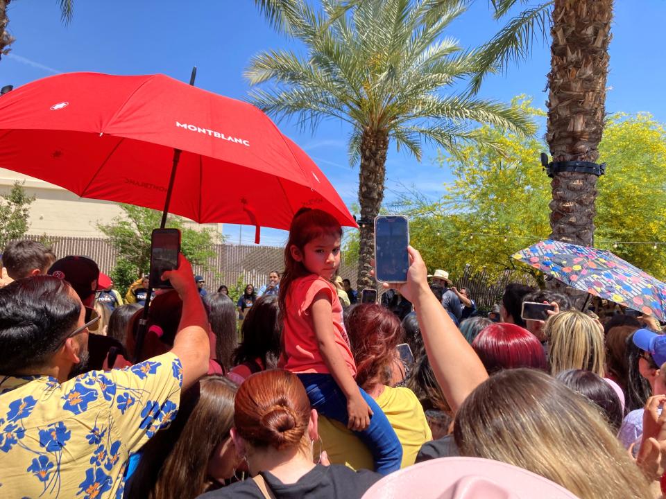 A young girl sits on someone's shoulders while people around her hold up their phones to capture popstar Becky G at the Coachella Library on Saturday.