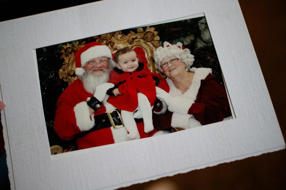 Tanya Axsom holds a picture of Emma Grace Cole and Santa on Tuesday, Dec. 7, 2021, inside her home in Bloomington, Ind. Axsom was Cole's guardian for much of her short life.