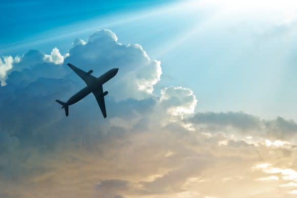 A plane gaining altitude against a sunlit background.