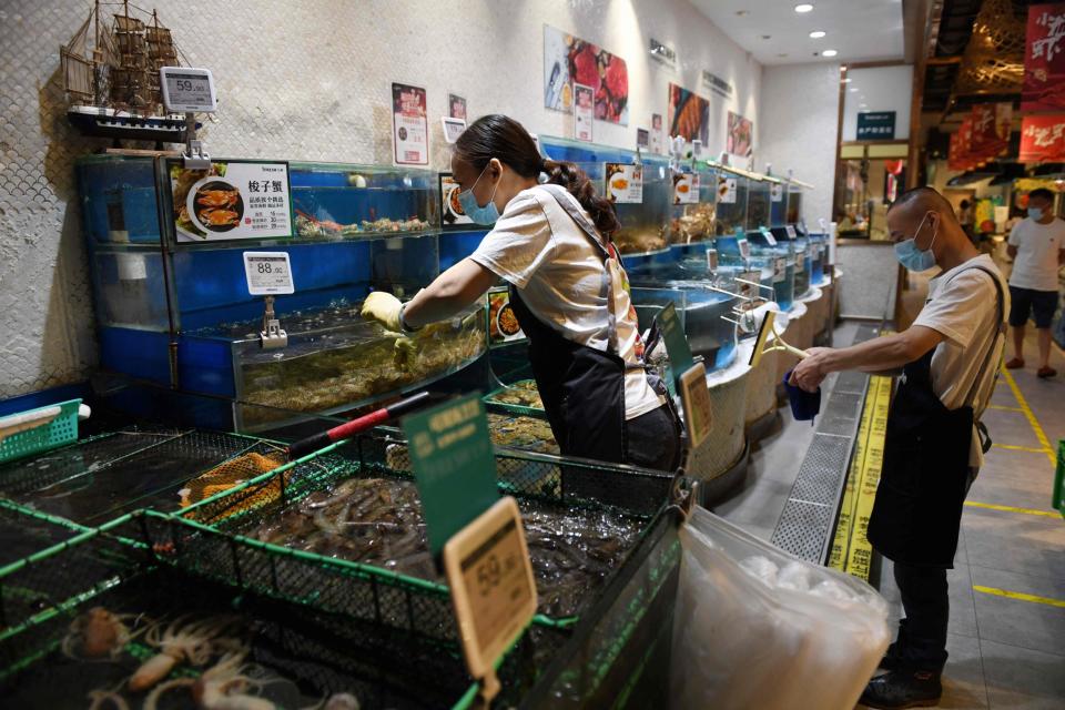 A worker is seen in the seafood section of a supermarket in Beijing on June 17, 2020 ( GREG BAKER/AFP via Getty Images)