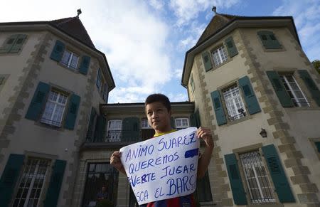 Ten year old Carlos, a Barcelona FC supporter and fan of Uruguayan striker Luis Suarez, holds a placard while standing in front of the Court of Arbitration for Sport (CAS) in Lausanne August 8, 2014. REUTERS/Denis Balibouse