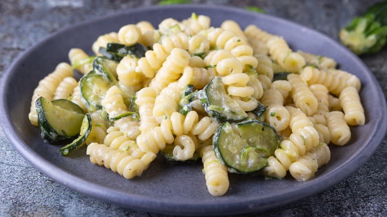 Goat cheese fussili with zucchini on a dark plate