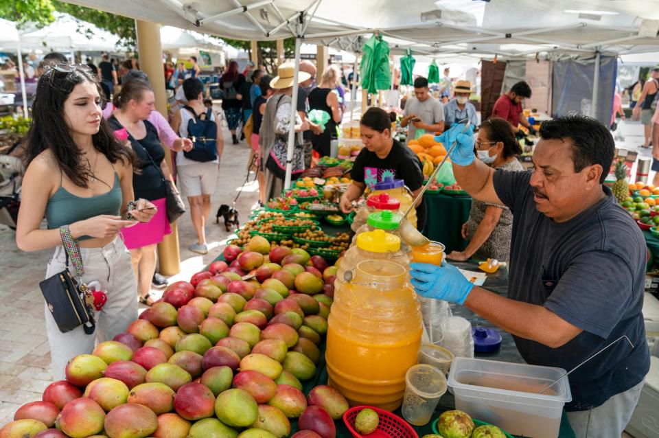 Adrian Loera makes fruit drinks at the West Palm Beach GreenMarket on October 8, 2022.