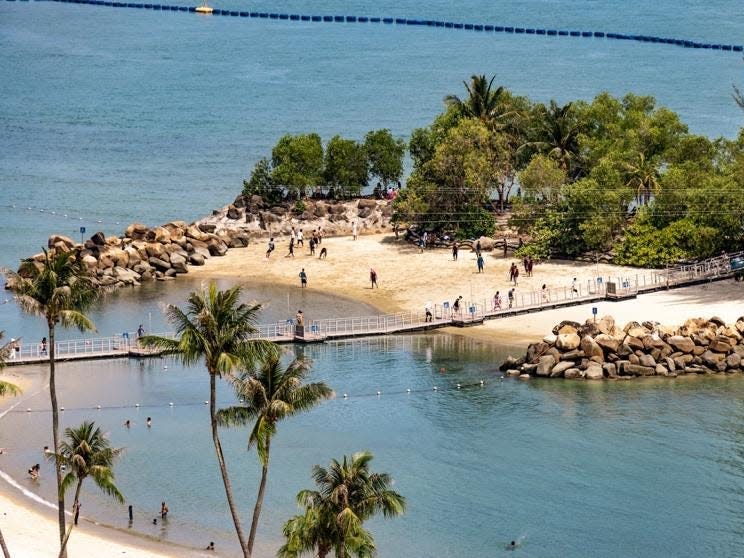 Tourists swim and cross a bridge on Sentosa Island in 2023.