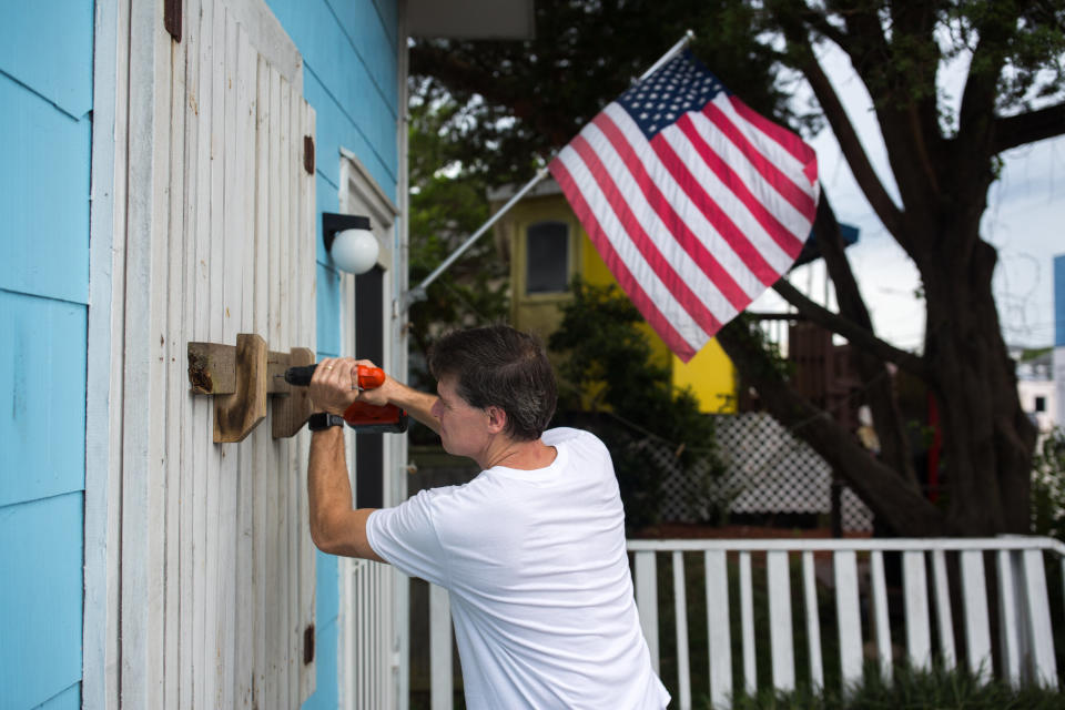 A man helps board up Aussie Island surf shop on Sept. 11, 2018, in Wrightsville, North Carolina.