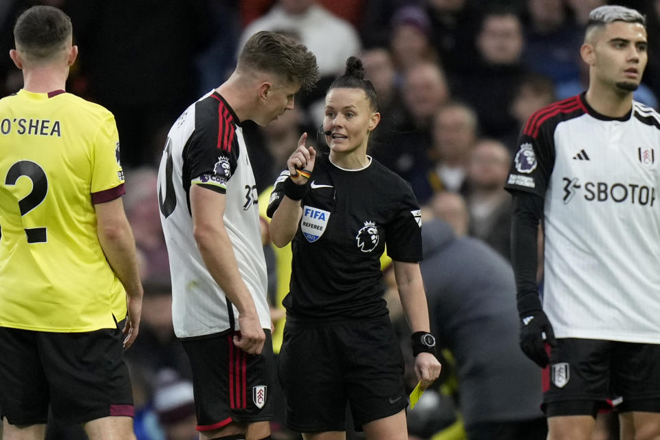 Referee Rebecca Welch holds a yellow card and speaks to Fulham's team captain Tom Cairney, before showing the card to Fulham's Calvin Bassey, during the English Premier League soccer match between Fulham and Burnley at Craven Cottage stadium in London, Saturday, Dec. 23, 2023. Welch is the first female referee ever to officiate an English Premier League game. (AP Photo/Alastair Grant)
