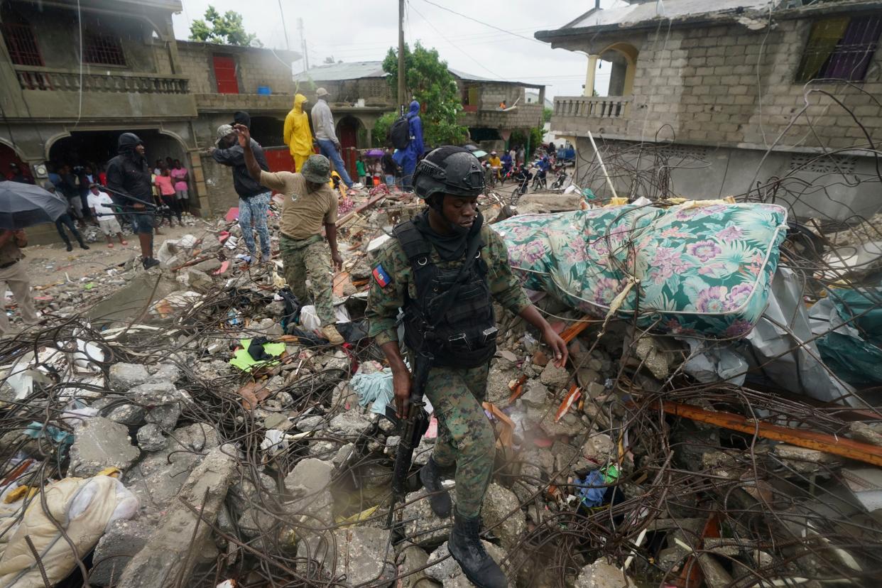 A soldier walks over earthquake rubble the morning after Tropical Storm Grace swept over Les Cayes, Haiti, Tuesday, Aug. 17, 2021, three days after the 7.2 magnitude quake.