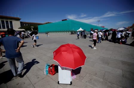 A tourist rests under an umbrella next to the installations set up on Tiananmen Square for the 70th anniversary of the founding of People's Republic of China in Beijing