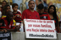 A fan holds a sign with a message that reads in Portuguese: "We feel the pain for the families, an entire nation weeps," as he waits for the start of a homage for the 10 teenage players killed by a fire at the Flamengo training center last Friday, at the Maracana Stadium, in Rio de Janeiro, Brazil, Thursday, Feb. 14, 2019, ahead of a soccer match between Flamengo and Fluminense. (AP Photo/Leo Correa)