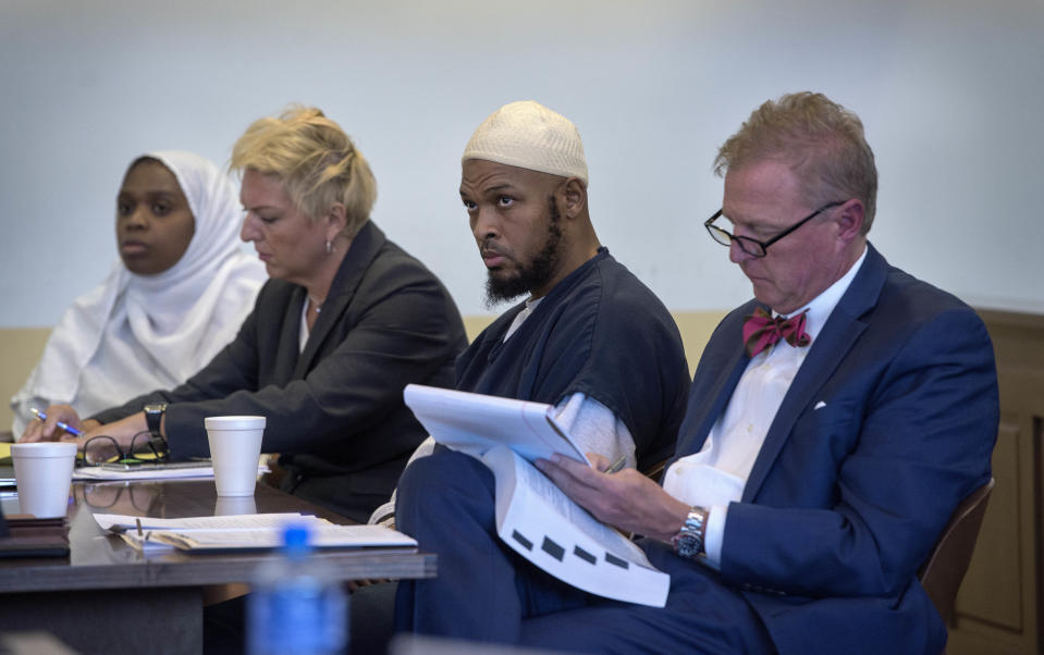 FILE - In this Aug. 29, 2018, file photo, Jany Leveille, from left, with her attorney Kelly Golightley, and Siraj Ibn Wahhaj with attorney Tom Clark listen to the prosecutor during a hearing on a motion to dismiss in the Taos County Courthouse. Federal prosecutors say the FBI has arrested five former residents, including Leveille and Wahhaj, of a ramshackle compound in northern New Mexico on firearms and conspiracy charges as local prosecutors dropped charges in the death of a 3-year-old boy at the property. Taos County District Attorney Donald Gallegos said Friday, Aug. 31, his office will now seek grand jury indictments involving the death. (Eddie Moore/The Albuquerque Journal via AP, Pool, File)
