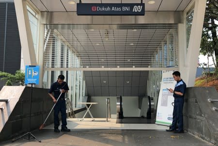 Workers stand outside a MRT station closed due to a major power blackout in Jakarta