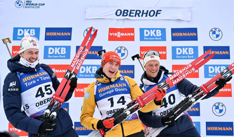 (L-R) Second placed Norway's Sturla Laegreid, winner Germany's Benedikt Doll and third placed Norway's Endre Stromsheim celebrate on the podium after the men's 10 km sprint event of the IBU Biathlon World Cup in Oberhof. Martin Schutt/dpa