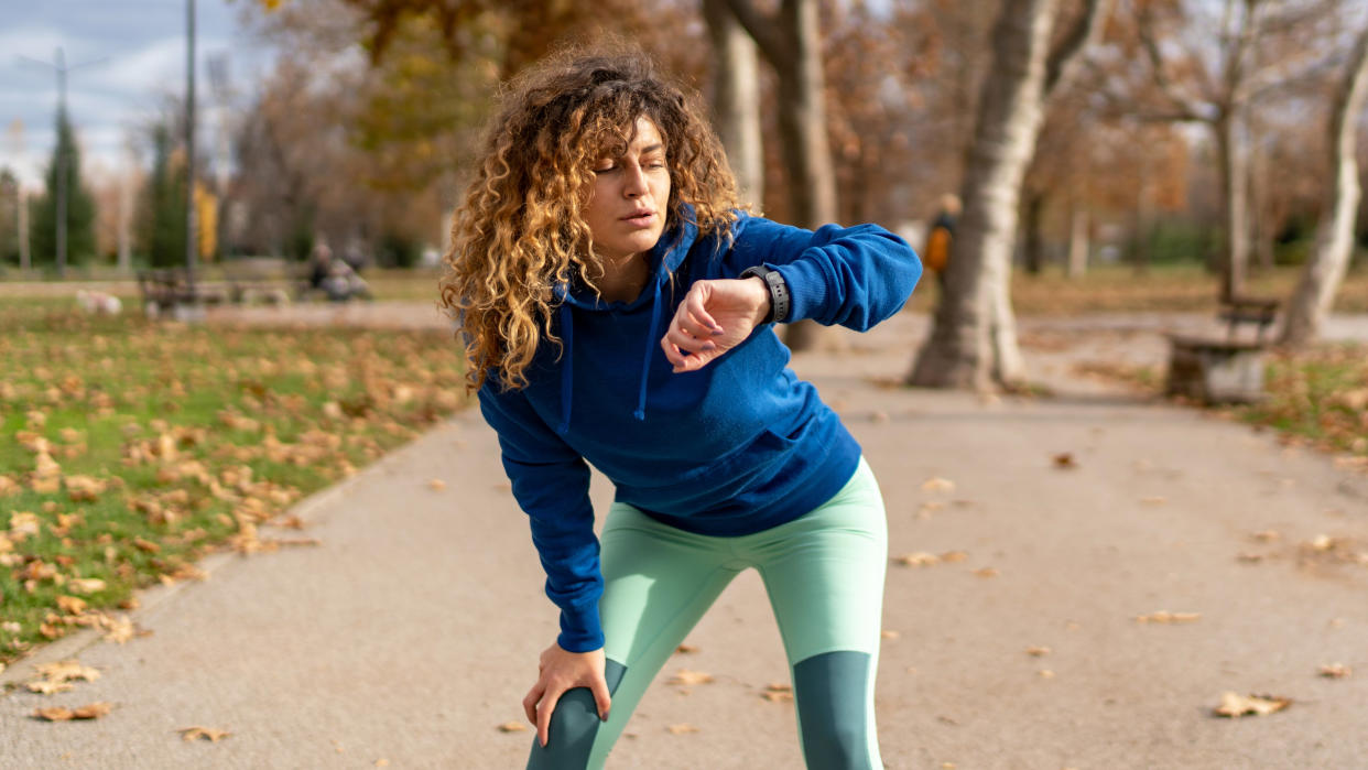  Woman checking GPS watch during run in park. 