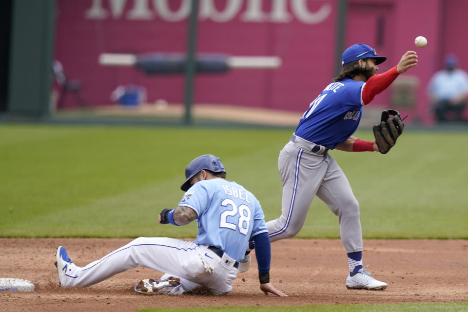 Toronto Blue Jays shortstop Bo Bichette, right, throws to first base after forcing out Kansas City Royals Kyle Isbel, left, during the second inning of a baseball game at Kauffman Stadium in Kansas City, Mo., Sunday, April 18, 2021. (AP Photo/Orlin Wagner)