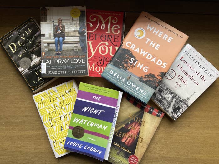 Photo of a spread of books including "The Devil in the White City," "Eat Pray Love," "Me Before You," "Where the Crawdads Sing," "Lovers at the Chameleon Club," "Mr. Penumbra's 24-Hour Bookstore," "The Night Watchman," and "Water for Elephants"