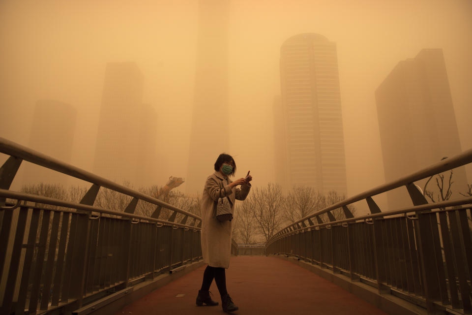 The Beijing sandstorm showing a woman barely visible on a a pedestrian bridge. (AP Photo)