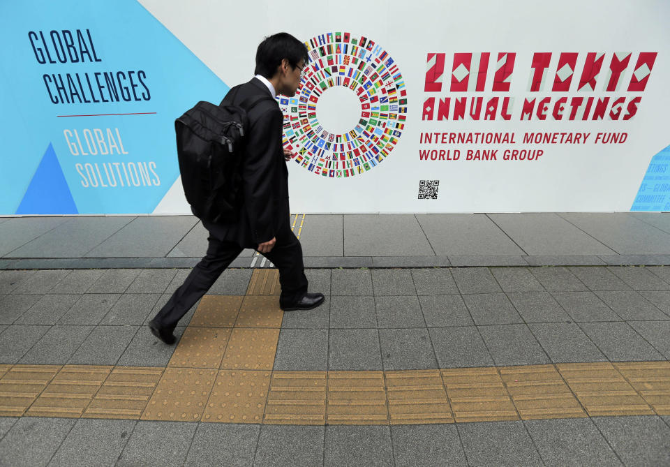 FILE - In this Wednesday, Oct. 10, 2012, file photo, a man walks in front of the venue of the International Monetary Fund and World Bank meeting. When global finance ministers meet this week in Tokyo, they'll confront a triple challenge: Economic troubles in three major regions are threatening the world's economy. (AP Photo/Itsuo Inouye, File)