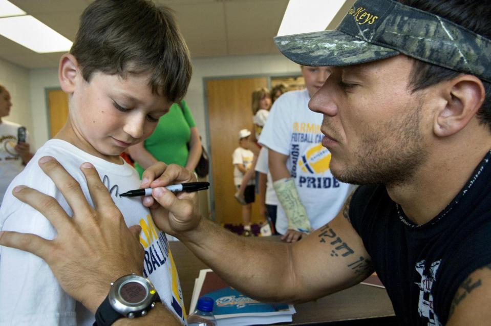 Former Canton, Illinois State and NFL player Boomer Grigsby signs the shirt of a camper during Grigsby's 2008 visit to Farmington.