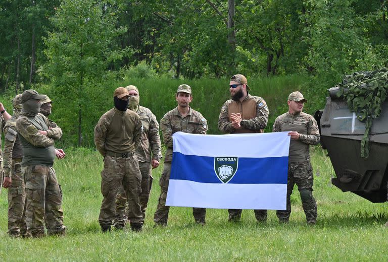 Comandos de la Legión Libertad de Rusia posan con una bandera en la rueda de prensa en la frontera