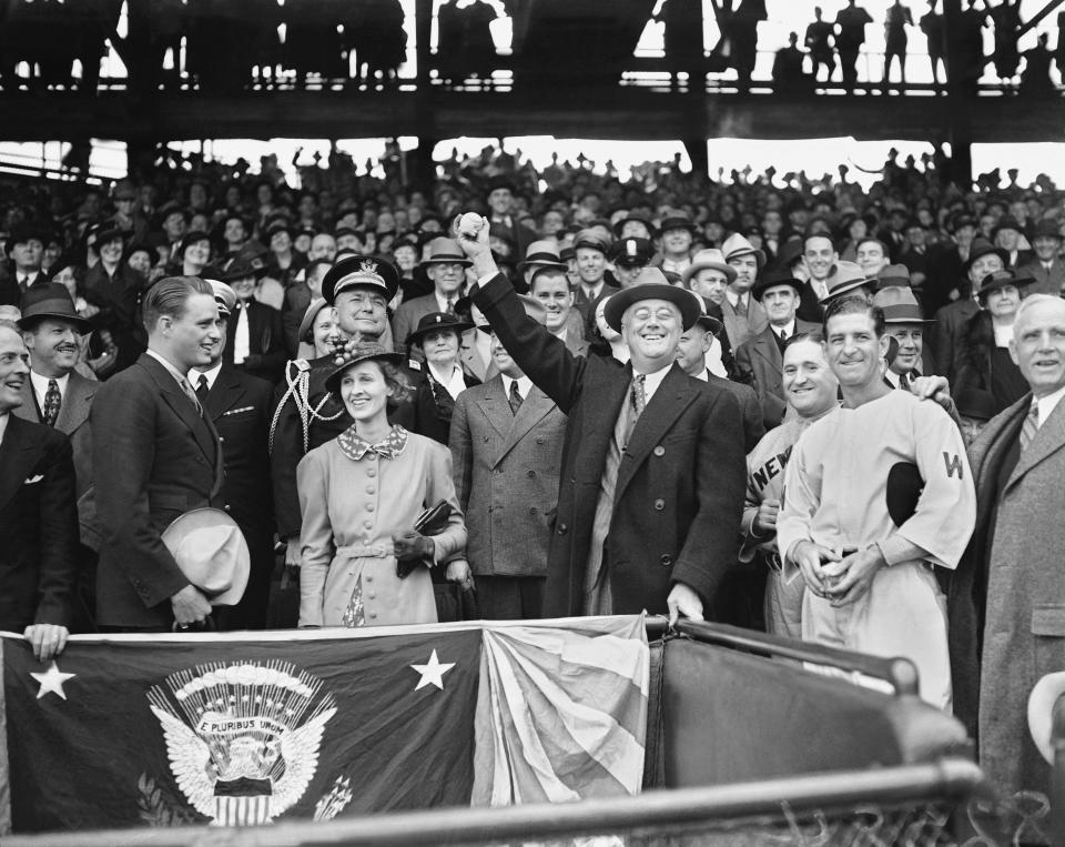 FILE - In this April 14, 1936, file photo, President Franklin D. Roosevelt prepares to throw the traditional first pitch in Washington, opening the baseball season with a game between the Senators and the Yankees at Griffith Stadium. From left: Roosevelt's son Elliott; Betsy Cushing Roosevelt, wife of FDR's eldest son, James; the president; Yankees manager Joe McCarthy; and Senators manager Bucky Harris. (AP Photo)