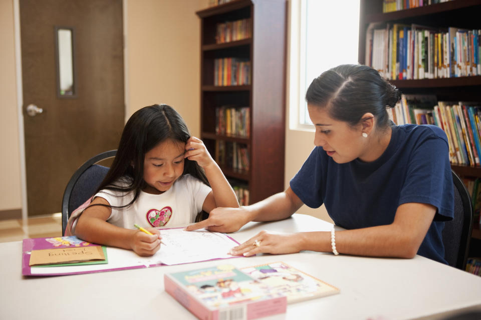 A woman helping a little girl with her homework