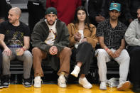 Rapper Bad Bunny, second from left, watches during the first half of an NBA basketball game between the Los Angeles Lakers and the Oklahoma City Thunder Tuesday, Feb. 7, 2023, in Los Angeles. (AP Photo/Marcio Jose Sanchez)