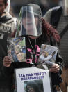 A woman wearing a mask amid the new coronavirus pandemic holds an image of a person who was disappeared, during a protest in front of the National Palace in Mexico City, Thursday, June 4, 2020. Relatives of different groups searching for the disappeared protested the cut to the budget destined for their search. (AP Photo/Eduardo Verdugo)