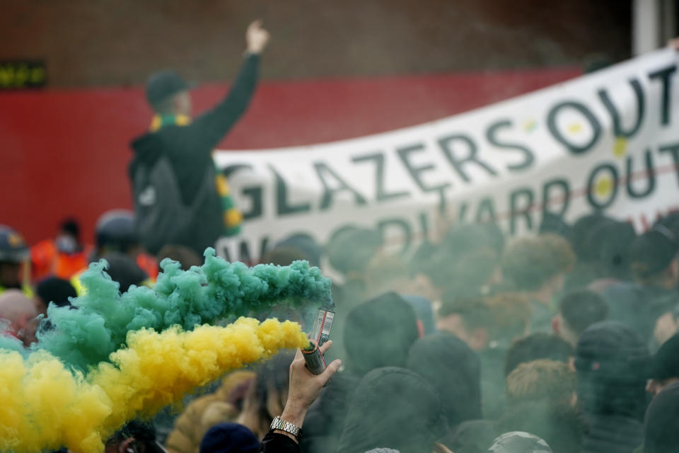 Manchester United fans let off flares as they protest against the Glazer family, the American owners of Manchester United, before their English Premier League soccer match against Liverpool at Old Trafford stadium in Manchester, England, Thursday, May 13, 2021. (AP Photo/Jon Super)