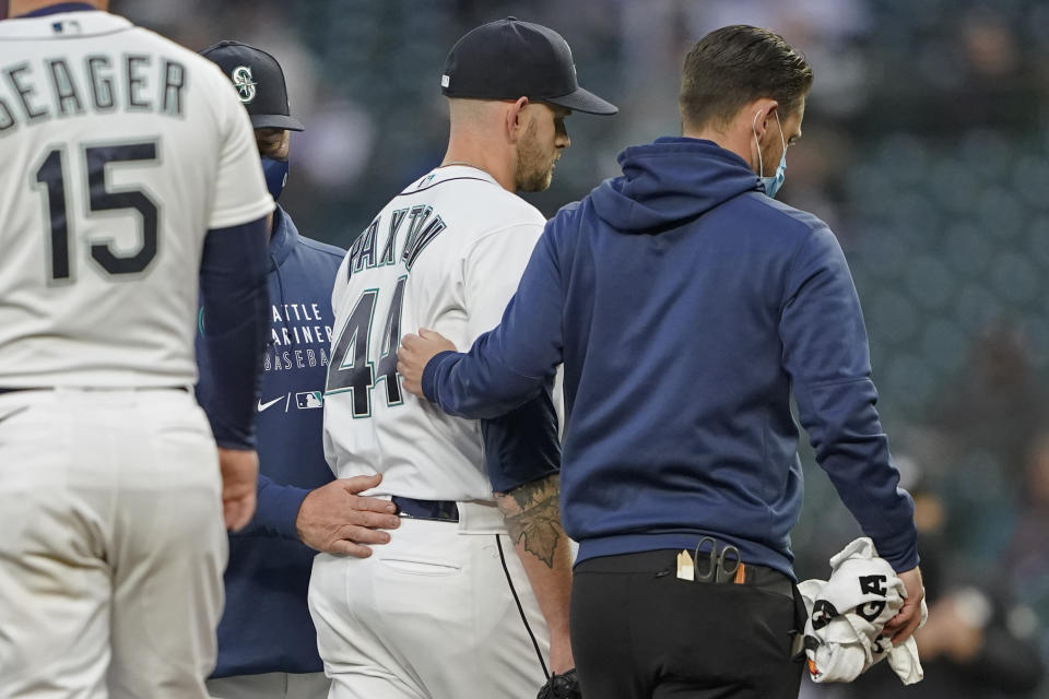 Seattle Mariners starting pitcher James Paxton, center, leaves the mound with a trainer, right, and manager Scott Servais during the second inning of the team's baseball game against the Chicago White Sox, Tuesday, April 6, 2021, in Seattle. Paxton was replaced by Nick Margevicius. (AP Photo/Ted S. Warren)