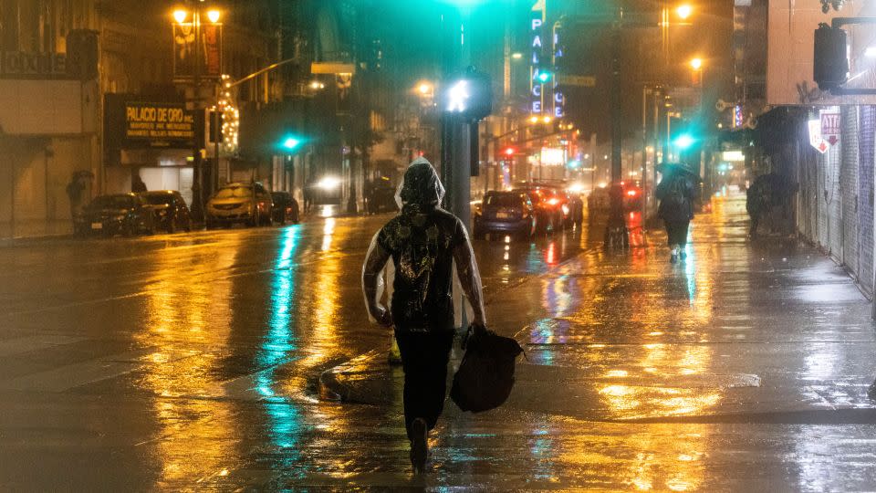 People walk Sunday during heavy rains in downtown Los Angeles. - Aude Guerrucci/Reuters