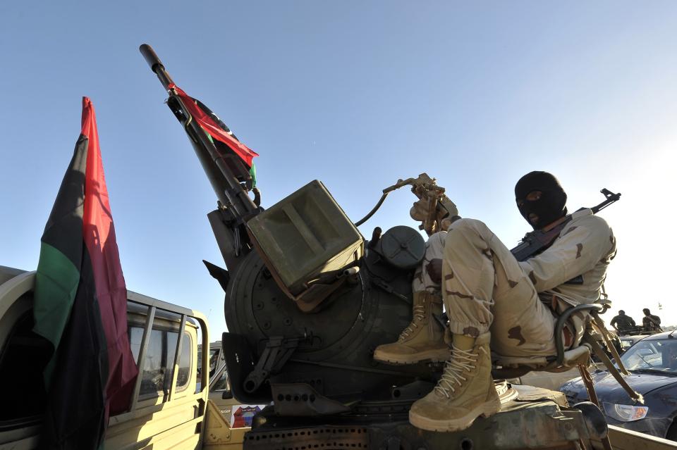 A member of the Libyan army's Thunderbolt Brigade sits at the back of a vehicle as the army prepares for deployment in Benghazi
