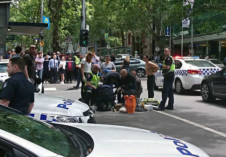 Members of the public watch as police and emergency services attend to an injured person after a car hit pedestrians in central Melbourne, Australia, January 20, 2017. AAP/Luke Costin/via REUTERS