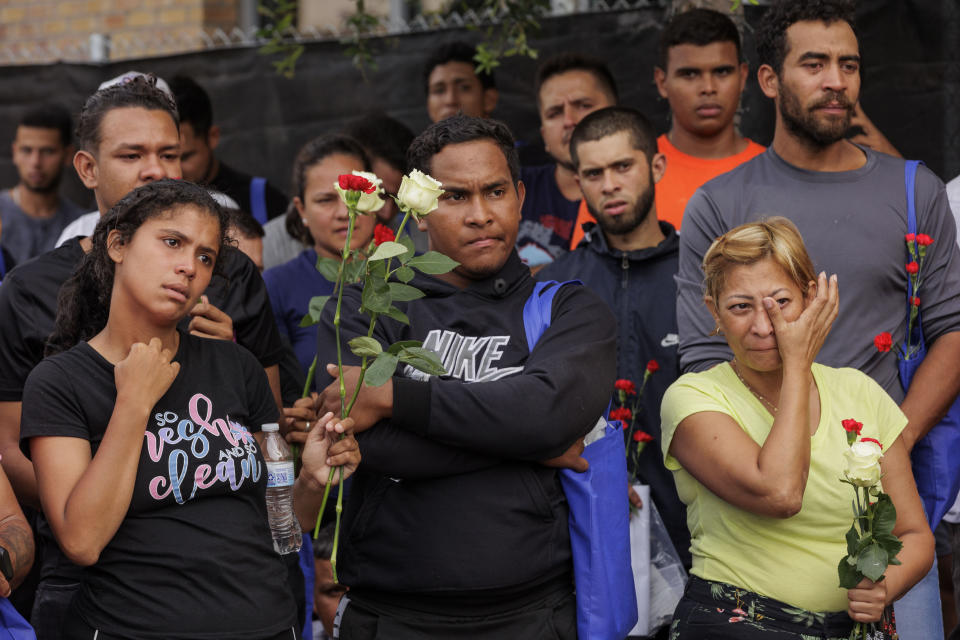 Migrants hold flowers and listen to speakers during a vigil for the eight migrants that were killed and several others that were injured the day before while waiting at a bus stop, in Brownsville, Texas, Monday, May 8, 2023. (AP Photo/Michael Gonzalez)