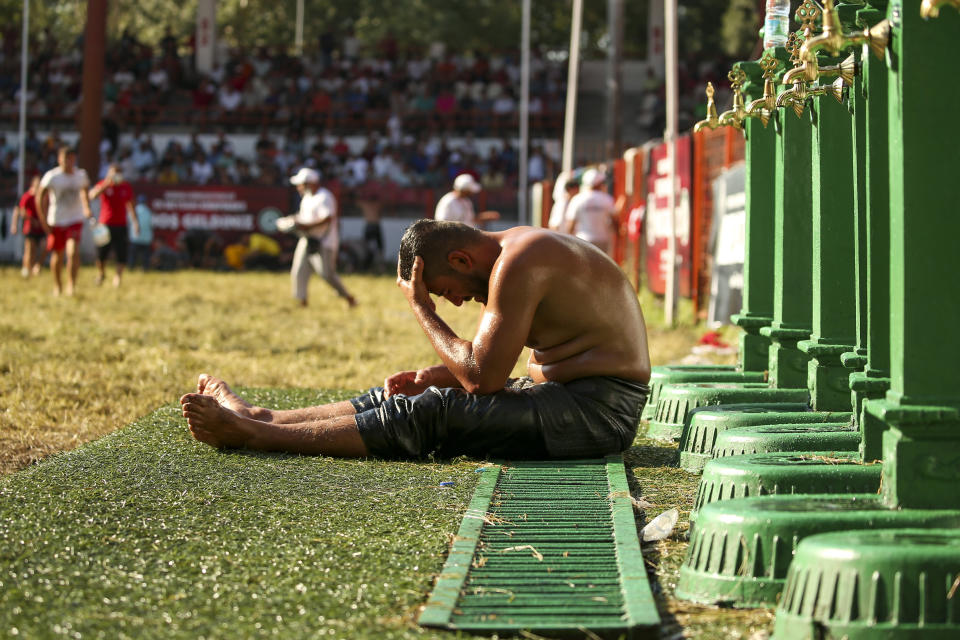 An exhausted wrestler tries to cool off after he competed on the second day of the 660th instalment of the annual Historic Kirkpinar Oil Wrestling championship, in Edirne, northwestern Turkey, Saturday, July 10, 2021.Thousands of Turkish wrestling fans flocked to the country's Greek border province to watch the championship of the sport that dates to the 14th century, after last year's contest was cancelled due to the coronavirus pandemic. The festival, one of the world's oldest wrestling events, was listed as an intangible cultural heritage event by UNESCO in 2010. (AP Photo/Emrah Gurel)