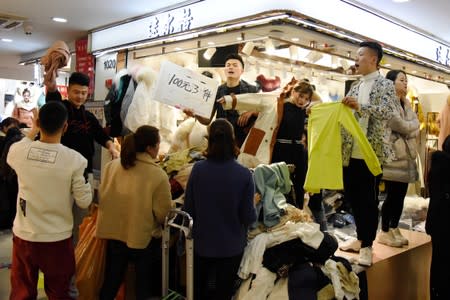 Vendors call out sale discounts to attract consumers at a clothing wholesale market ahead of the Chinese Lunar New Year, in Hangzhou