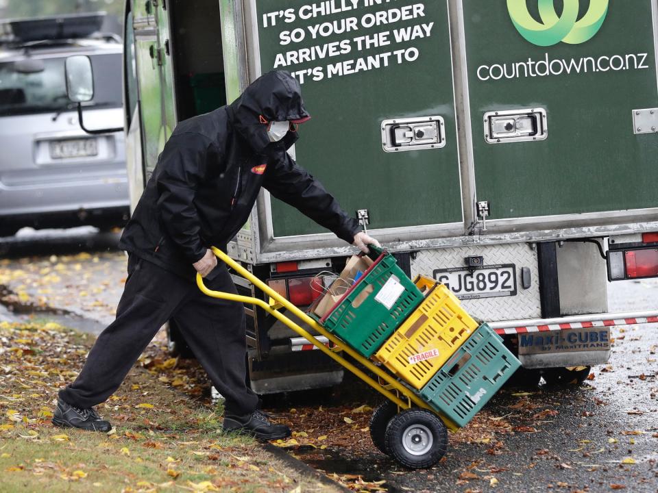 A delivery driver wearing a face mask delivers groceries to a home on March 30, 2020.