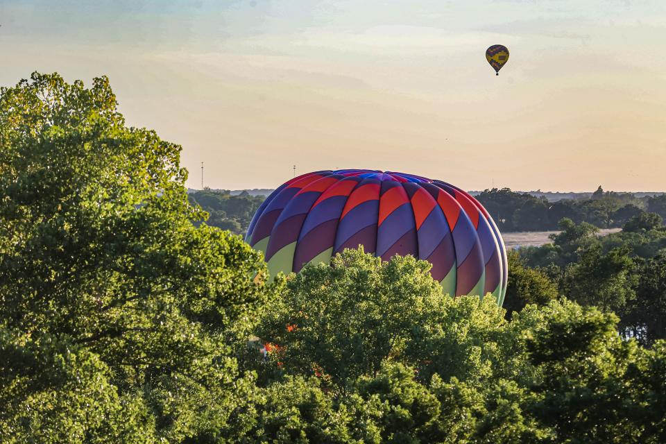 A multi-colored hot-air balloon emerges as balloons take flight at the FireLake Fireflight Balloon Fest on Thursday, Aug. 11, 2022, in Shawnee.