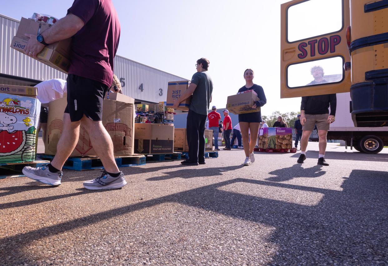 Seniors from Walsh Jesuit High School help unload a Marlington Local school bus at the Akron-Canton Regional Foodbank's Stark County campus Tuesday in Canton. Volunteers helped unload food as part of the seventh annual "Hunger: The Bus Stops Here" fundraising drive.